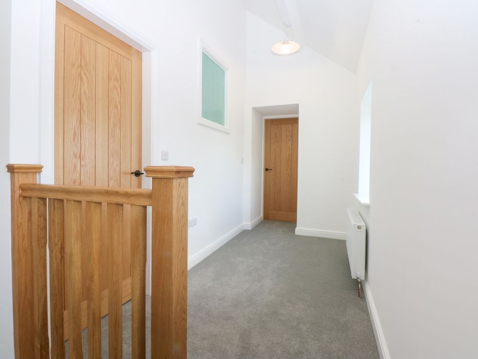 A hallway with wooden doors and a railing at Trefor Ganol Beaumaris
