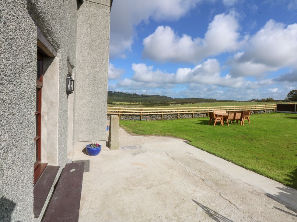 A table and chairs on grass with a door at Trefor Ganol Beaumaris
