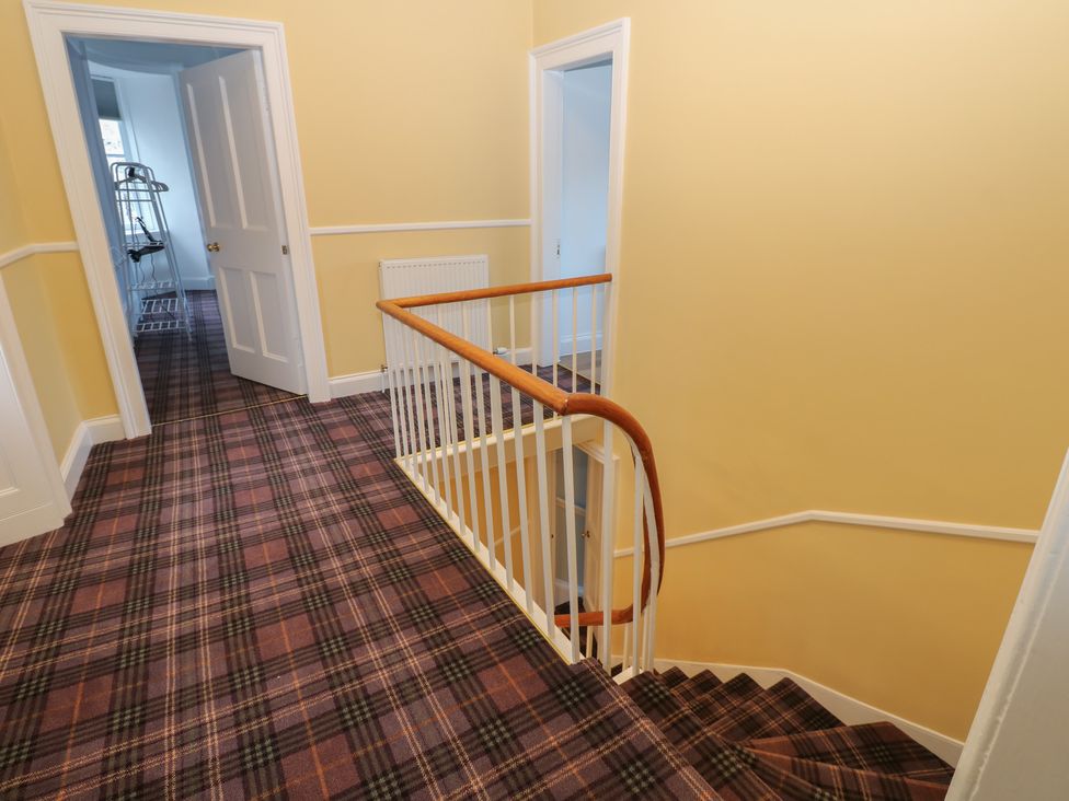 A hallway with stairs and doors at Eskvale House in Langholm