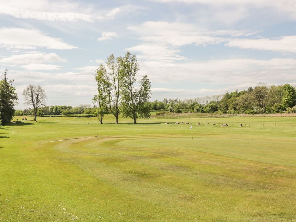 A golf course with trees and a flag at King's Apartment