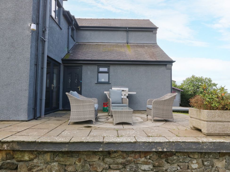 Outdoor patio with seating and a grill at Tyn Rallt in Newborough