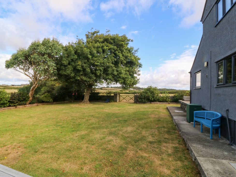 A garden with a tree and a fence at Tyn Rallt in Newborough