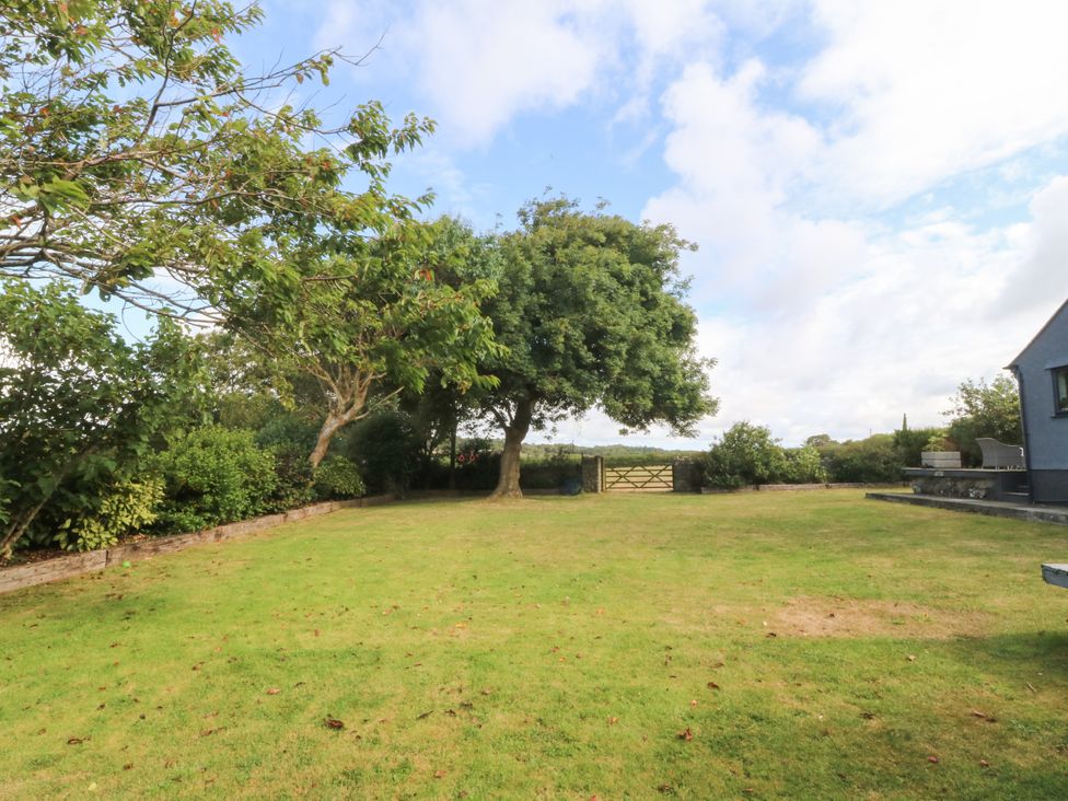 A garden with a tree and gate at Tyn Rallt Newborough