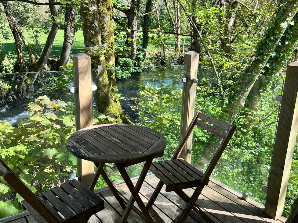 A table and chairs on an outdoor deck overlooking a stream at Glas y Dorlan Nevern near Newport, Pembrokeshire