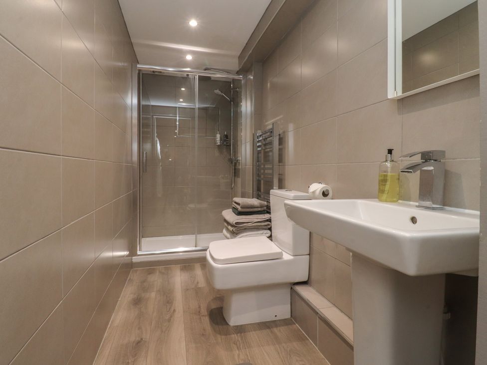 A bathroom with a shower, toilet, and sink at Paramount Apartments in Lytham St. Annes