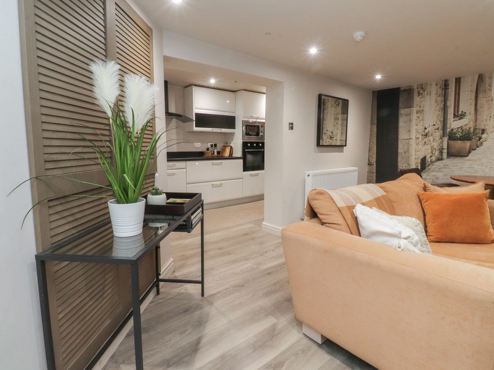 A living room with a couch and kitchen area at Paramount Apartments in Lytham St. Annes
