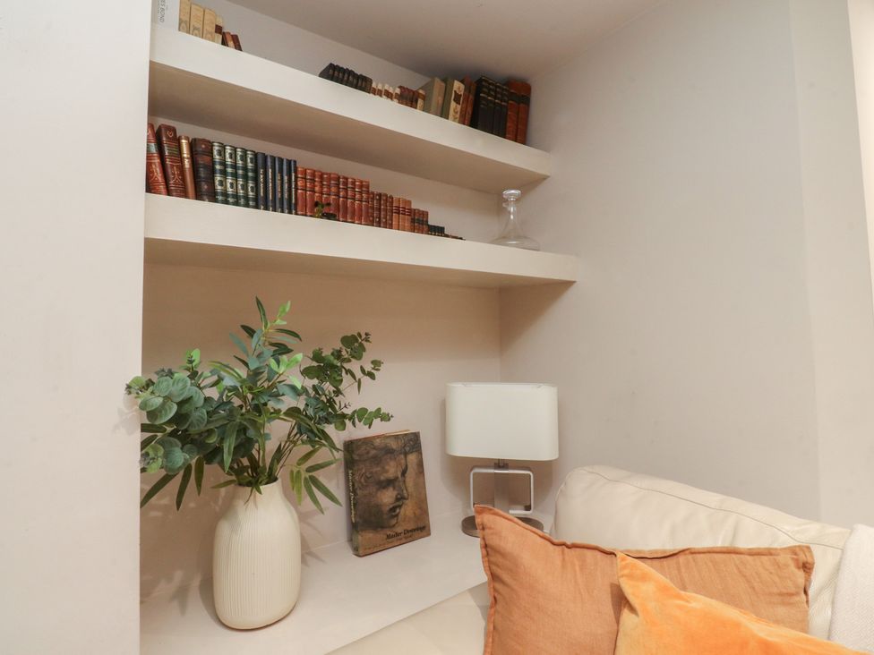 A living room with books and a plant on a shelf at Paramount Apartments in Lytham St. Annes