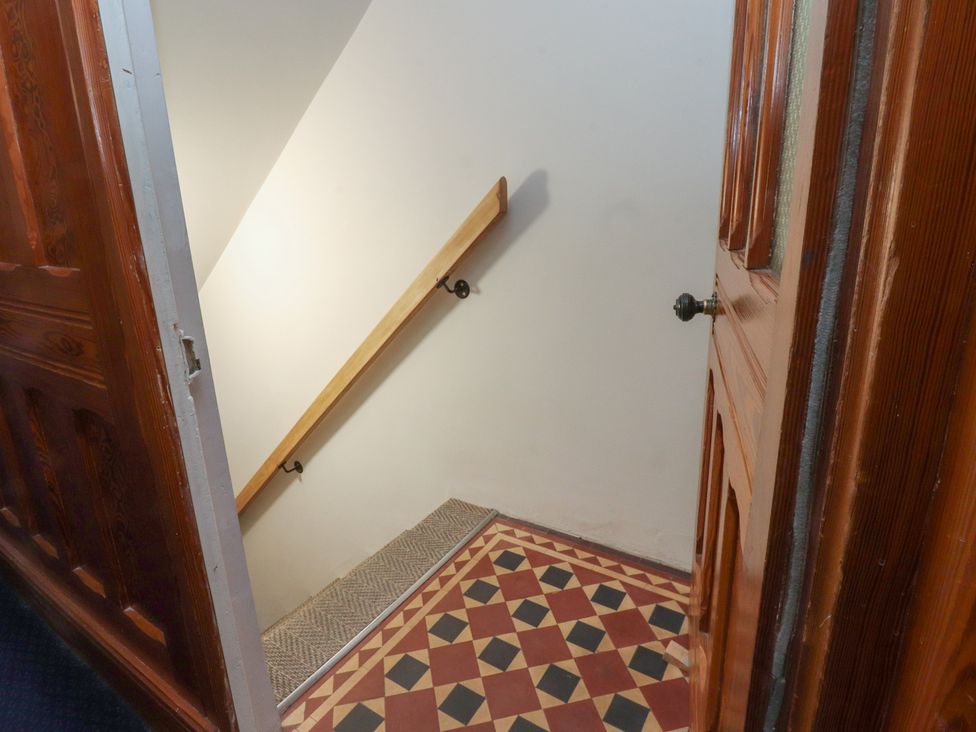 A staircase leading down with a door and decorative floor tiles at Paramount Apartments in Lytham St. Annes