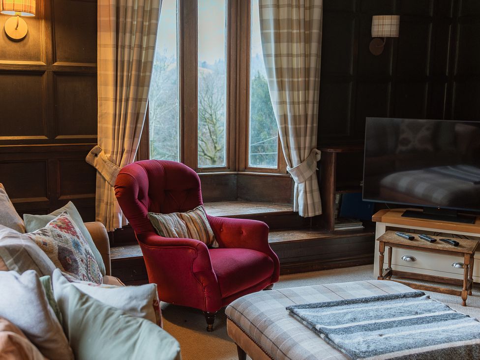 A living room with a red armchair and a television at Grey Walls in Glenridding