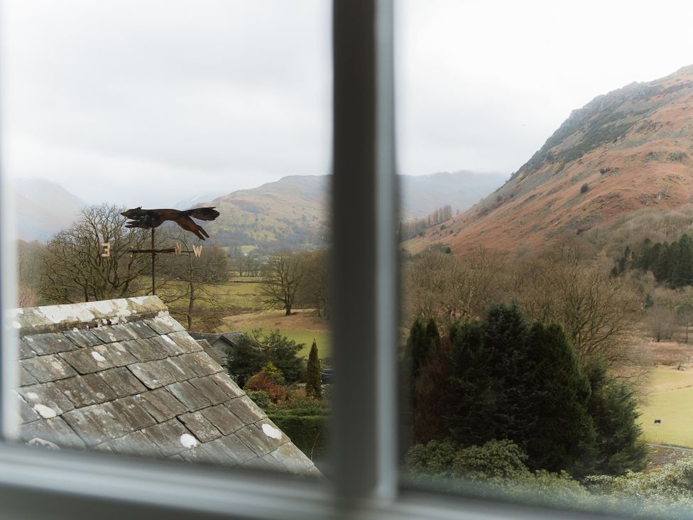 A view of mountains and trees from a window at Grey Walls in Glenridding