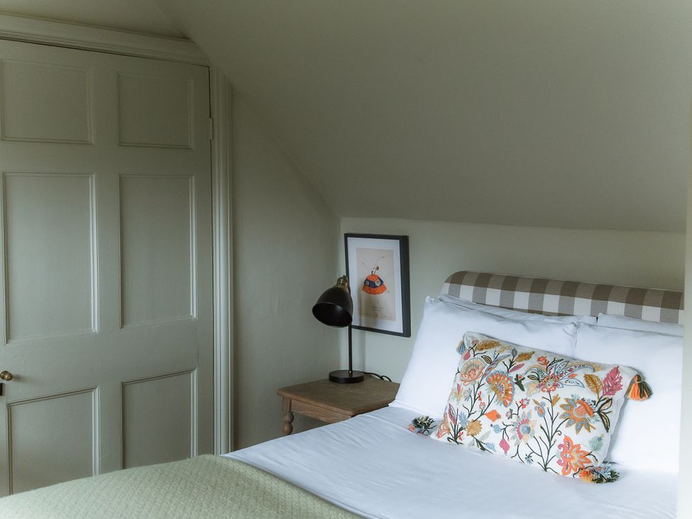 A bedroom with a bed, lamp, and framed picture at Grey Walls in Glenridding