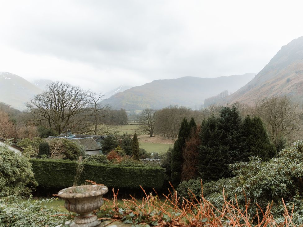A view of mountains and trees from a garden at Grey Walls in Glenridding
