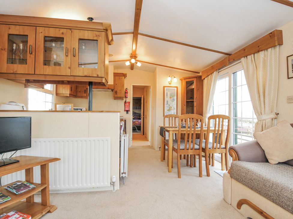 A living room with a tv, dining table, and chairs at Little Malory in St Giles-On-The-Heath