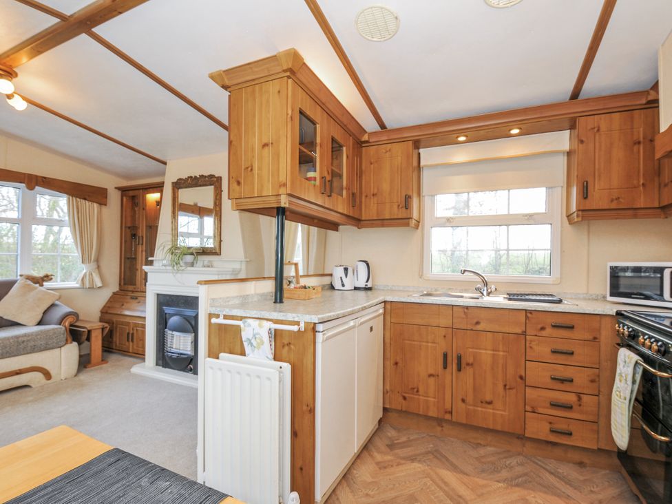 A kitchen with wooden cabinets and appliances at Little Malory in St Giles-On-The-Heath