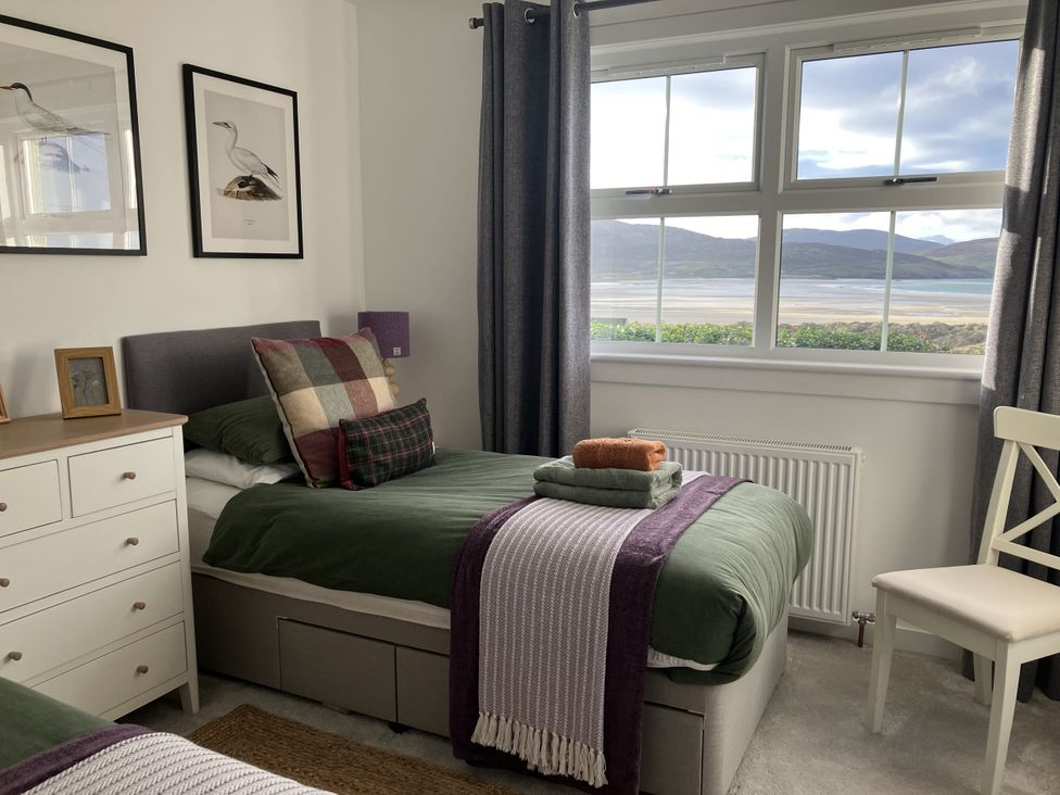 A bedroom with two beds and a view outside at Taigh Marsaili, Luskentyre, Isle Of Harris