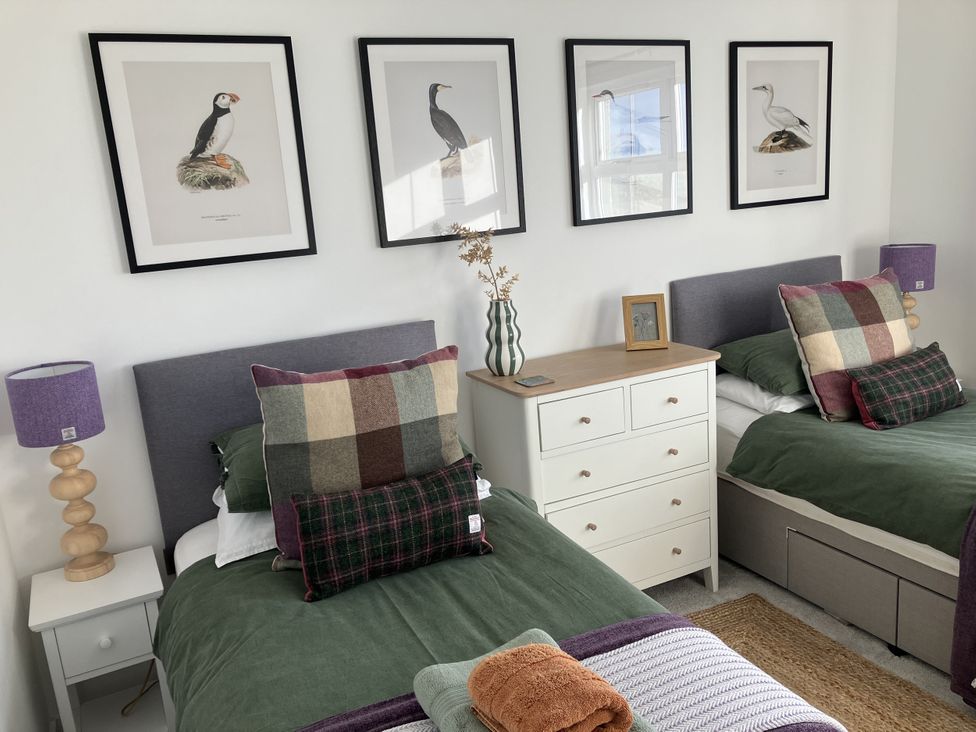 A bedroom with two beds and framed prints on the wall at Taigh Marsaili, Luskentyre, Isle Of Harris