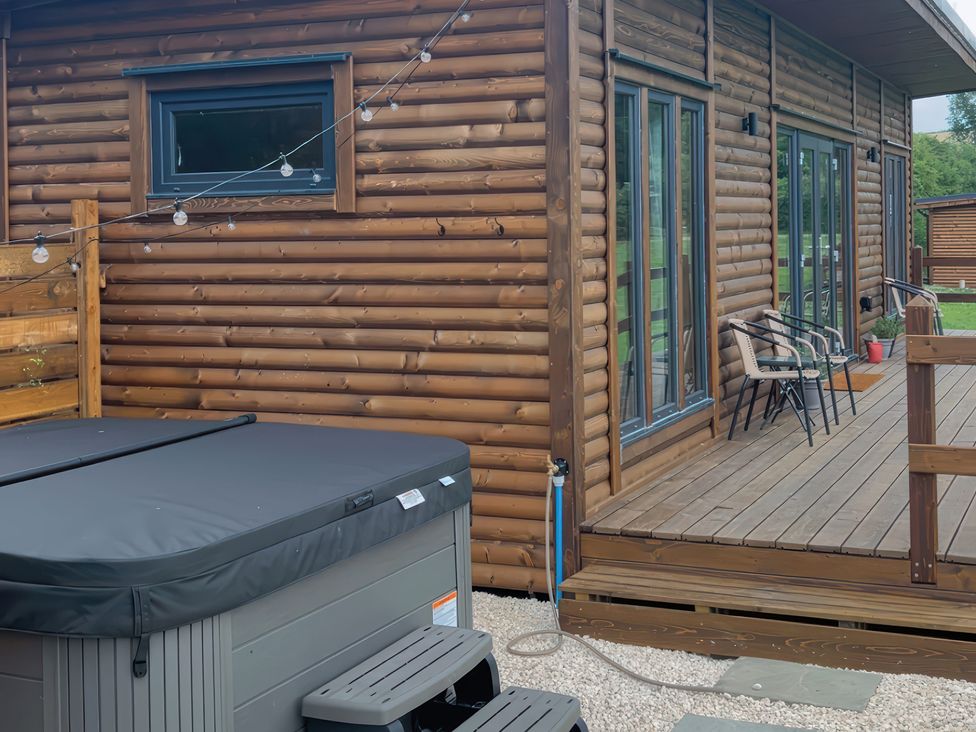 An outdoor area with a hot tub and chairs at Primrose in Higher Wambrook near Chard