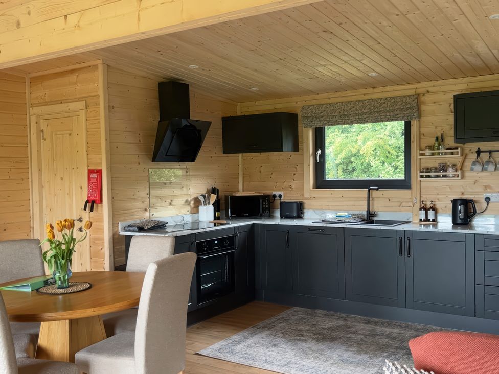 A kitchen with a dining table and a window at Primrose in Higher Wambrook near Chard