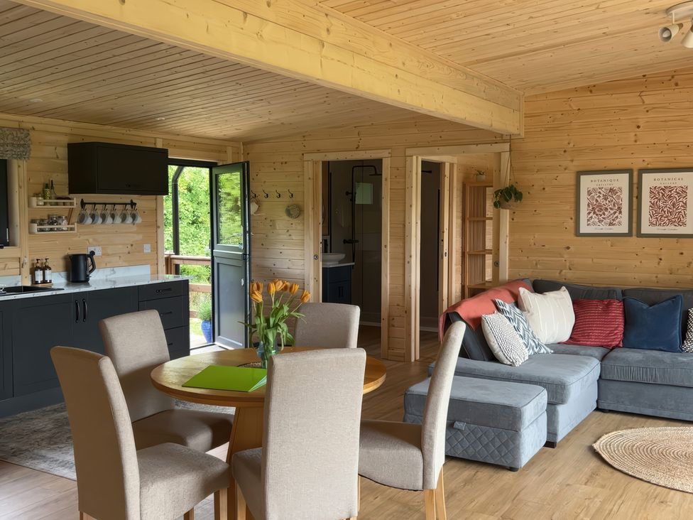 A living room with a sofa and dining area at Primrose in Higher Wambrook near Chard