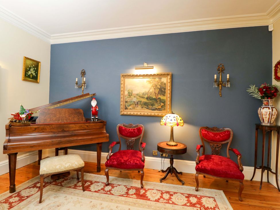 A living room with a grand piano and red chairs at the White House