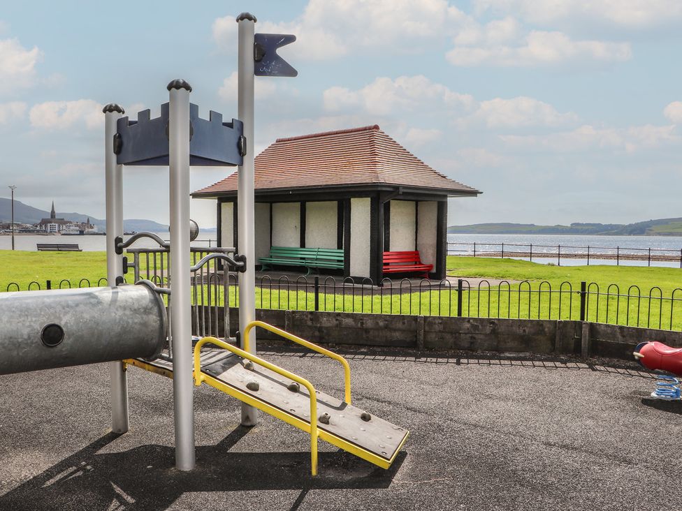 A playground with a slide and benches by the waterfront at The Old Rectory in Largs