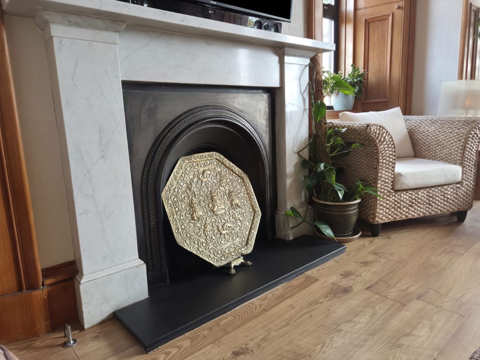 A living room with a fireplace and armchair at The Old Rectory in Largs
