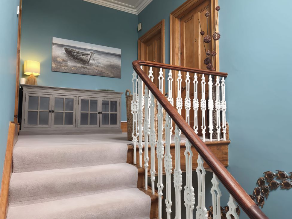 A hallway with a staircase and console table at The Old Rectory in Largs