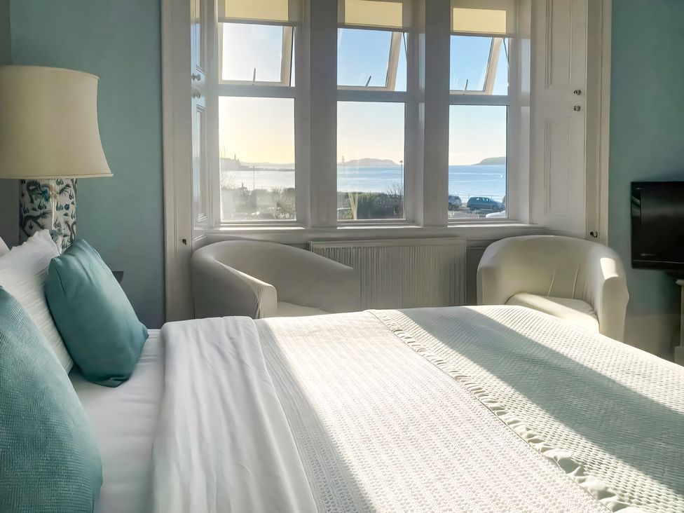 A bedroom with a bed and window overlooking the water at The Old Rectory in Largs