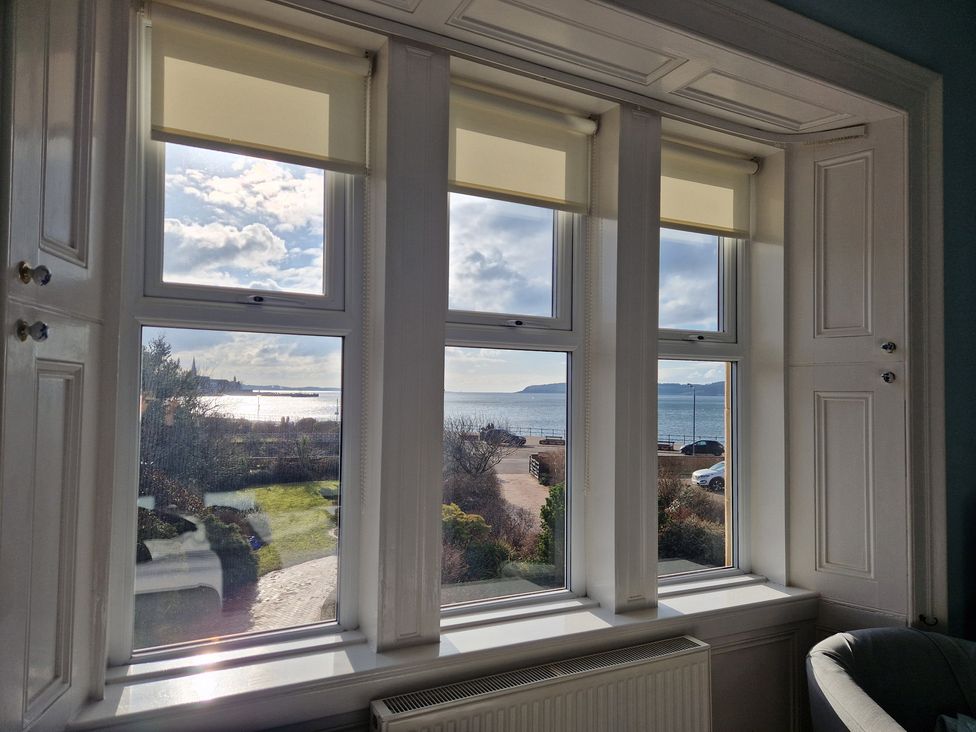 A living room with a sea view through three windows at The Old Rectory in Largs