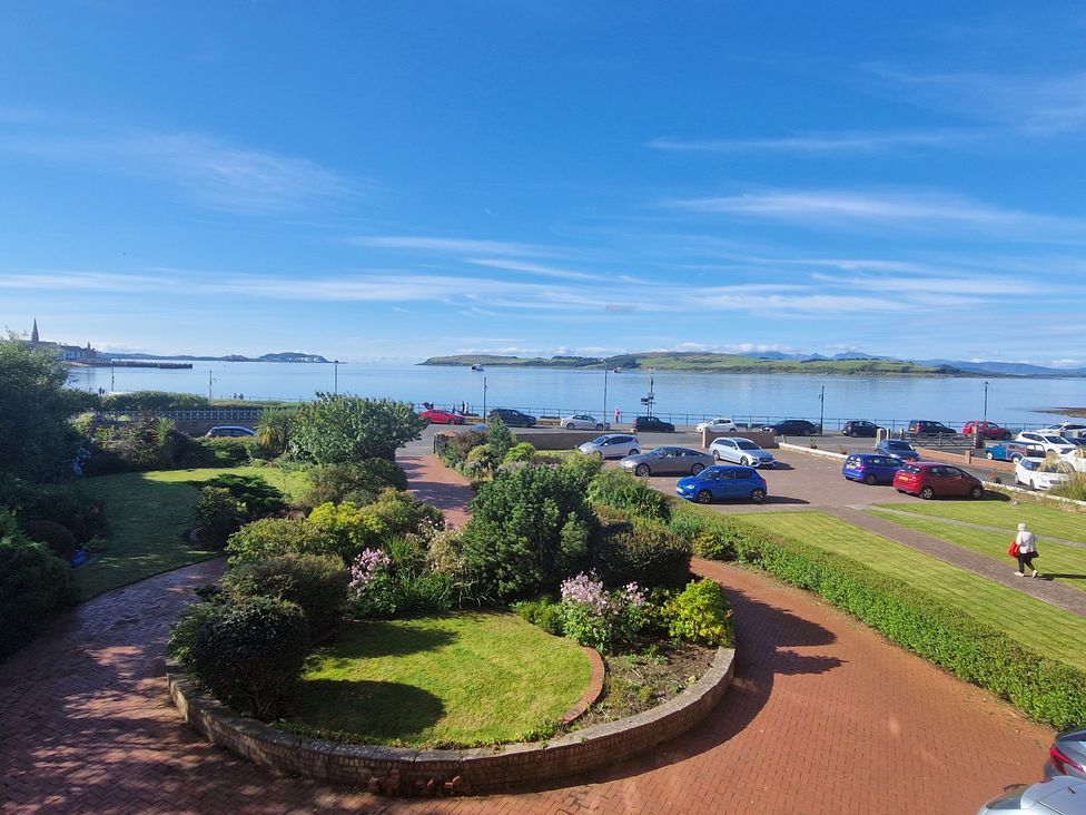 A view of the sea with cars parked and gardens at The Old Rectory in Largs