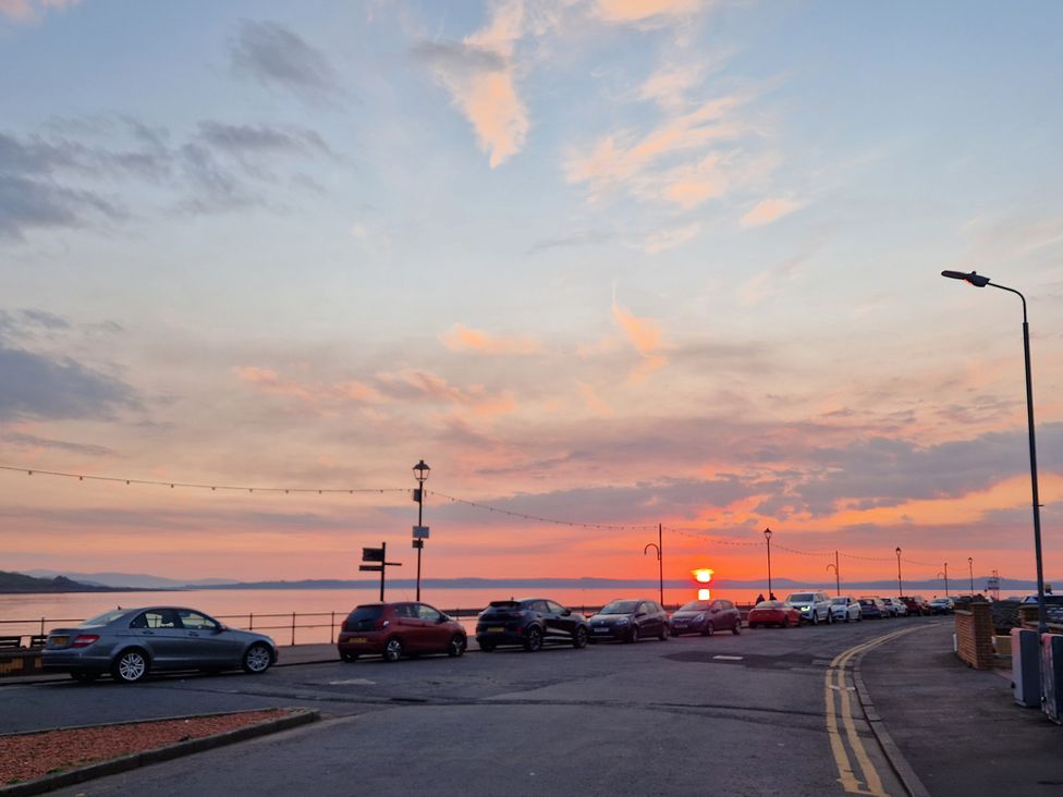 A street with parked cars by the ocean at sunset at The Old Rectory in Largs
