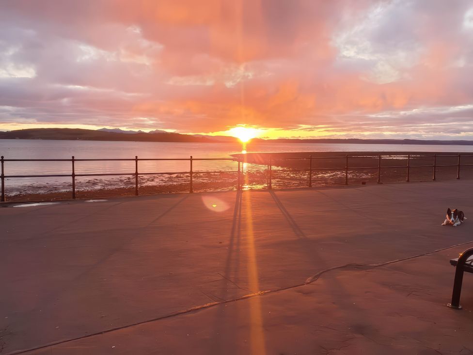 A sunset by a shoreline with a dog on the path at The Old Rectory in Largs
