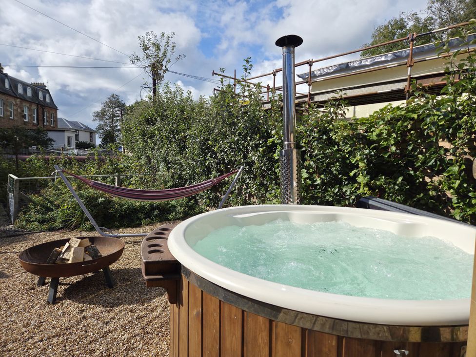An outdoor area with a hot tub, hammock, and fire pit at The Old Rectory in Largs
