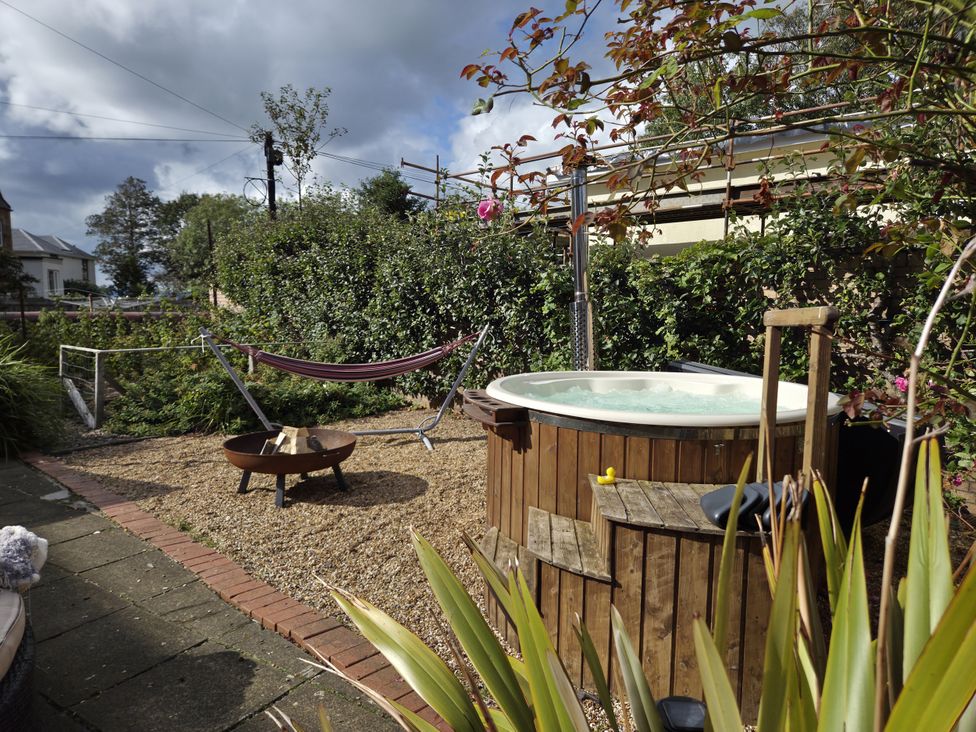 A garden with a hammock, fire pit, and hot tub at The Old Rectory in Largs