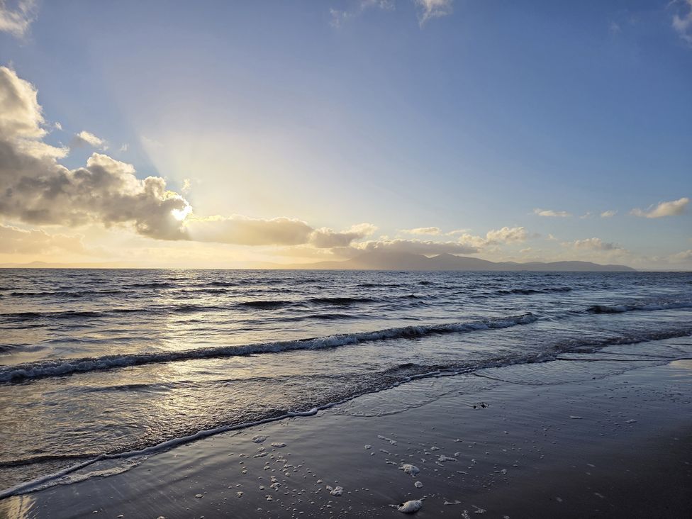 A beach with waves and clouds during sunset at The Old Rectory in Largs