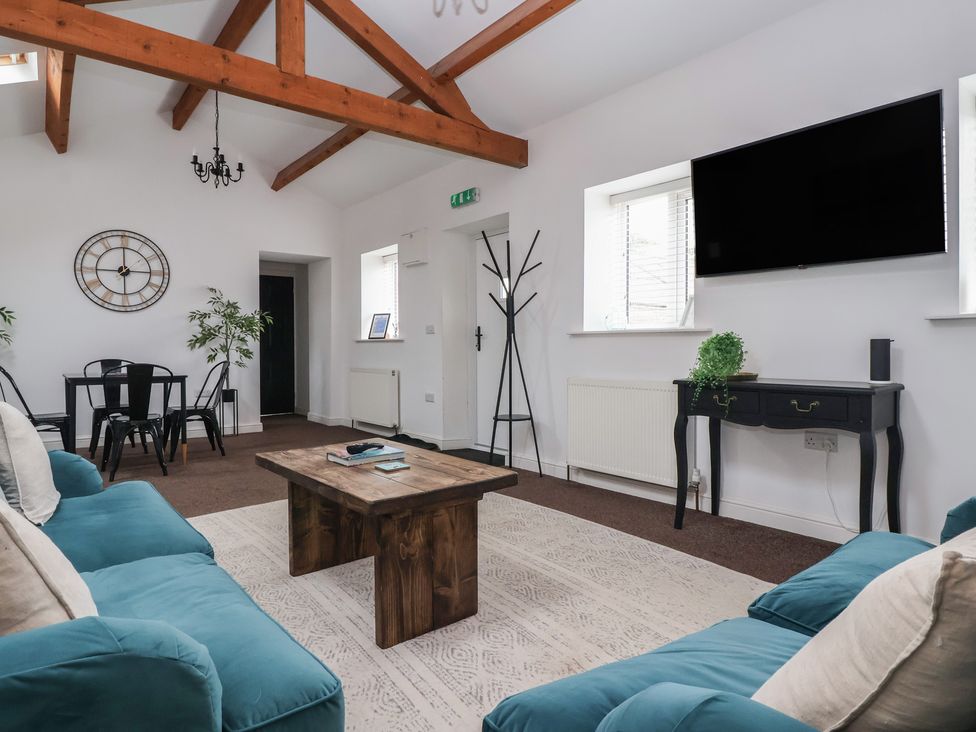 A living room with sofas, a table, and a television at Gannet in Flamborough