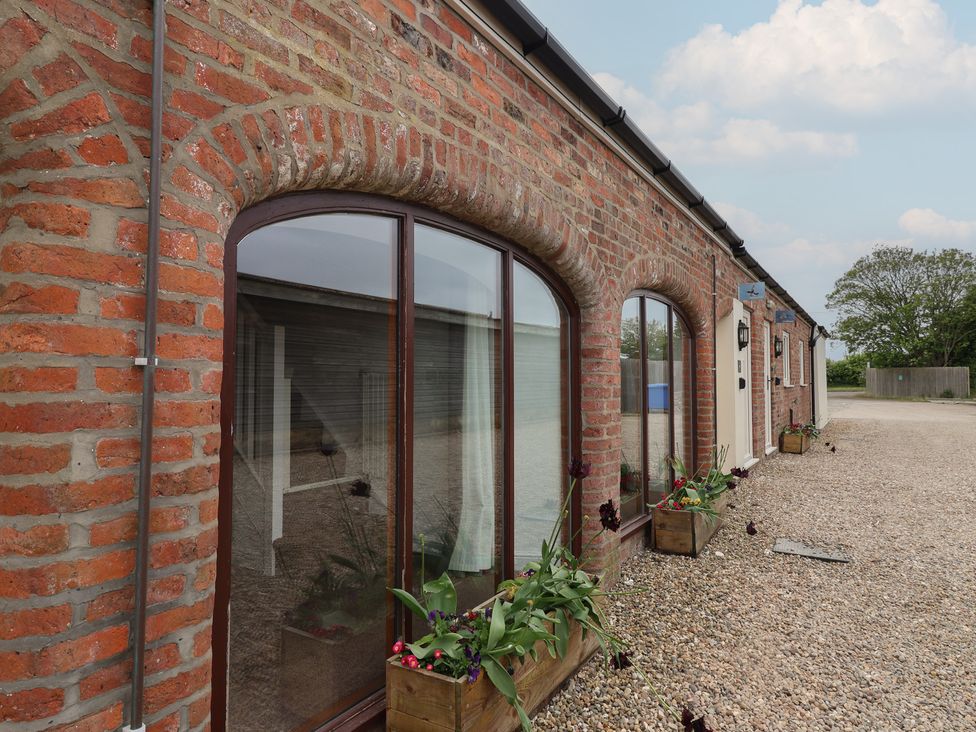 An exterior view of a brick building with windows and flower boxes at Razorbill in Flamborough