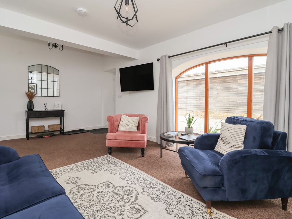 A living room with a blue sofa and a pink armchair at Razorbill in Flamborough