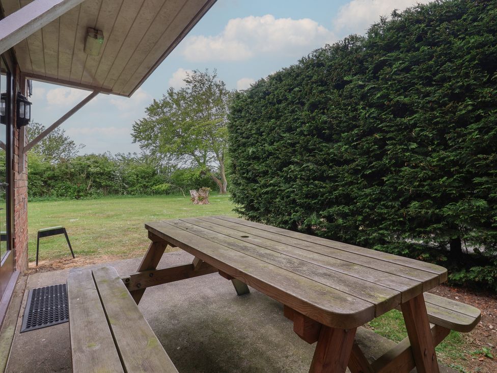 An outdoor seating area with a wooden table and benches at Razorbill in Flamborough