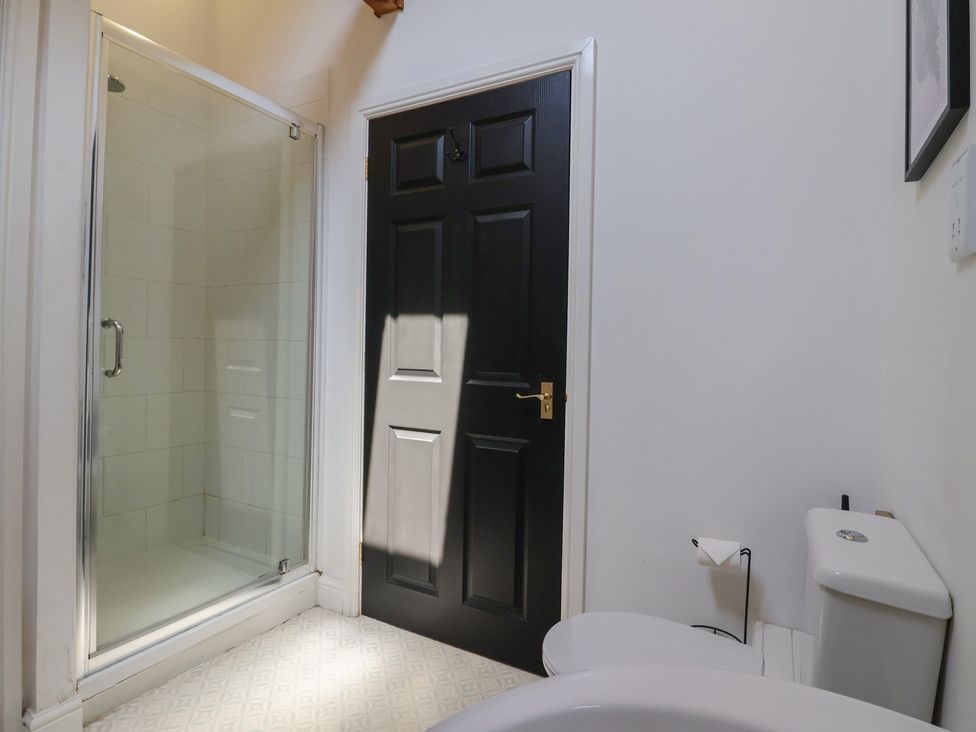 A bathroom with a shower enclosure a black door and a toilet at Guillemot in Flamborough