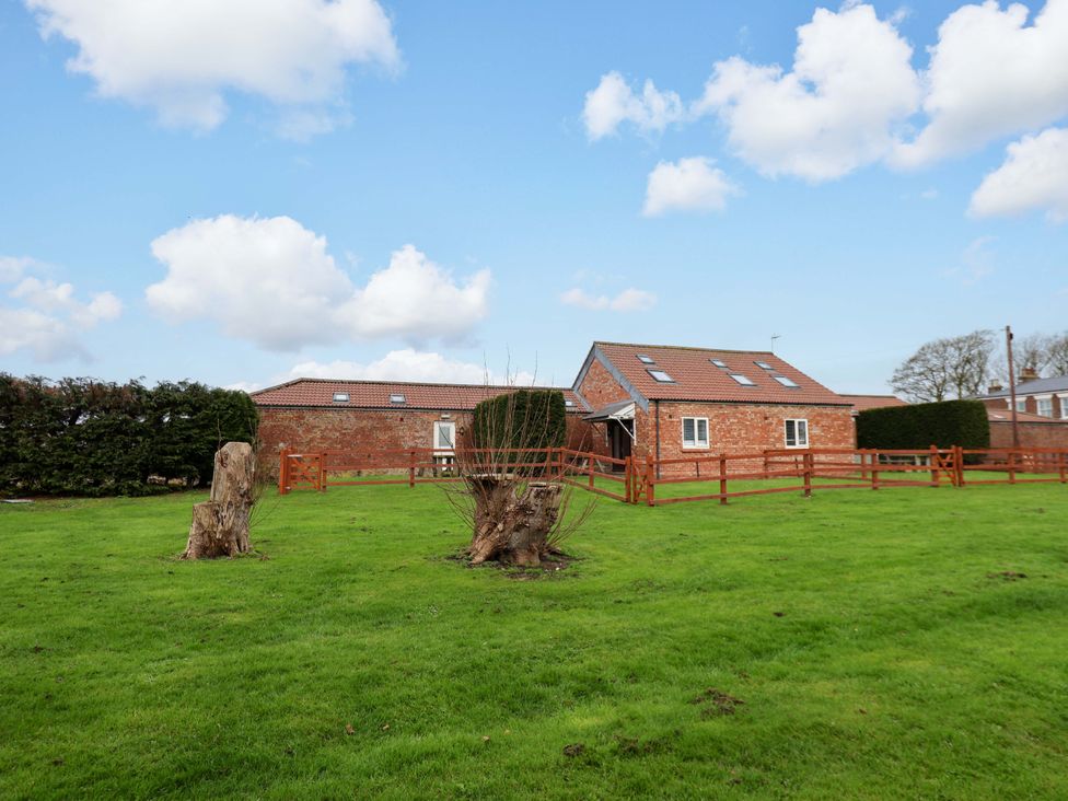 A house with a fence and tree stumps in an outdoor area at Guillemot in Flamborough