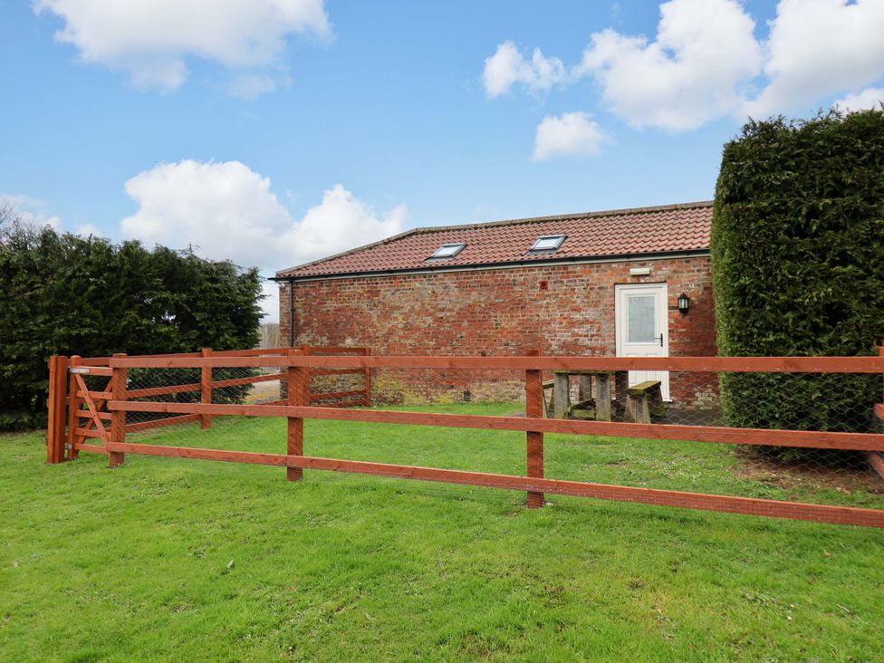 A garden area with a fenced enclosure and a door at Guillemot in Flamborough