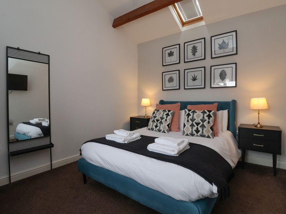 A bedroom with a bed and framed wall art at Puffin in Flamborough
