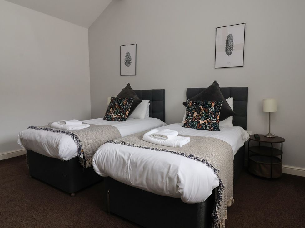 A bedroom with two single beds and a nightstand at Puffin in Flamborough