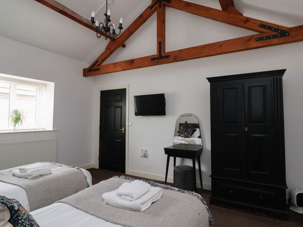 A bedroom with two beds and a wardrobe at Puffin in Flamborough