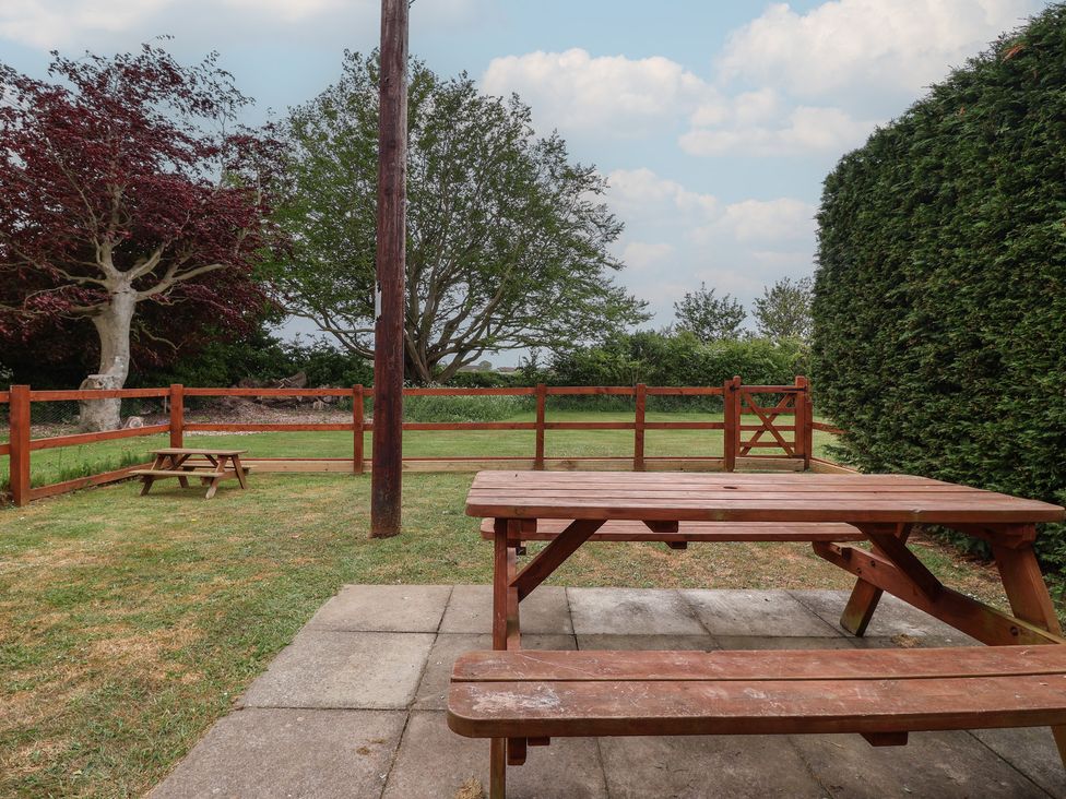 A garden with a wooden table and bench at Puffin in Flamborough