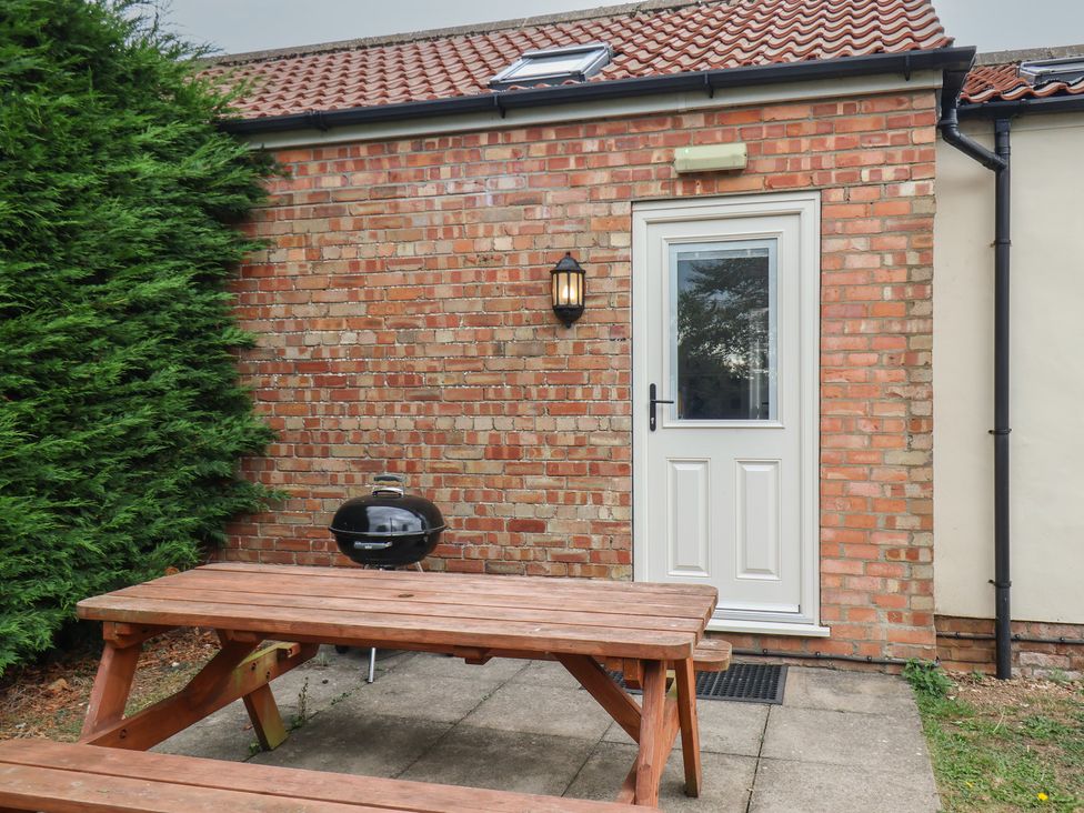 An outdoor area with a table and grill at Puffin in Flamborough