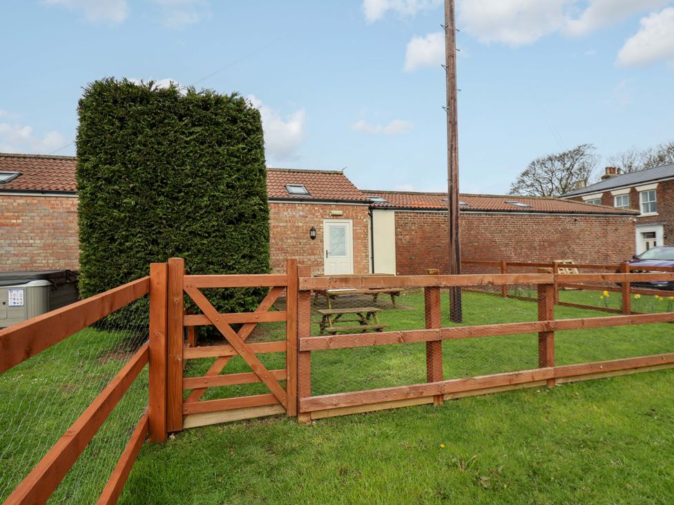 A garden with a fence and table at Puffin in Flamborough