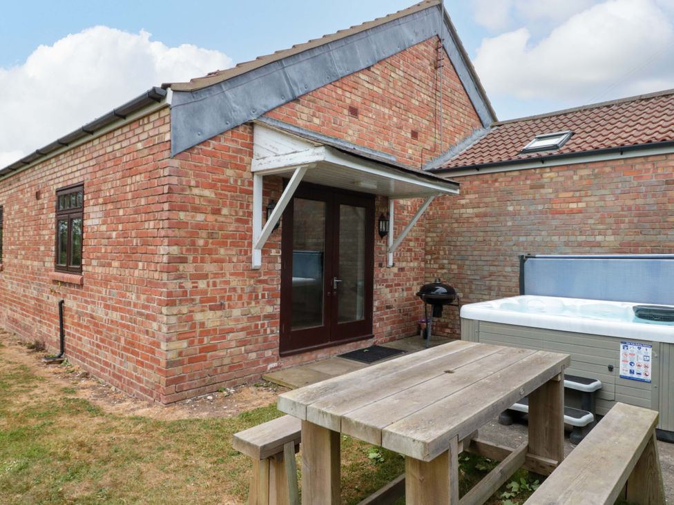An outdoor area with a hot tub and table at Kittiwake in Flamborough