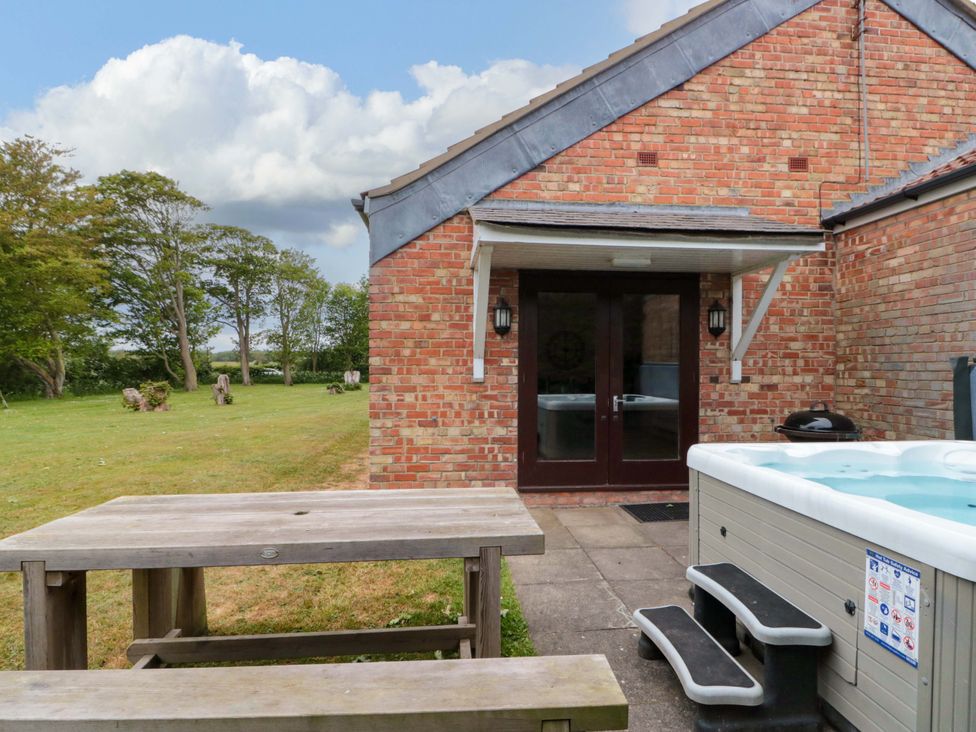 An outdoor area with a hot tub and picnic table at Kittiwake in Flamborough